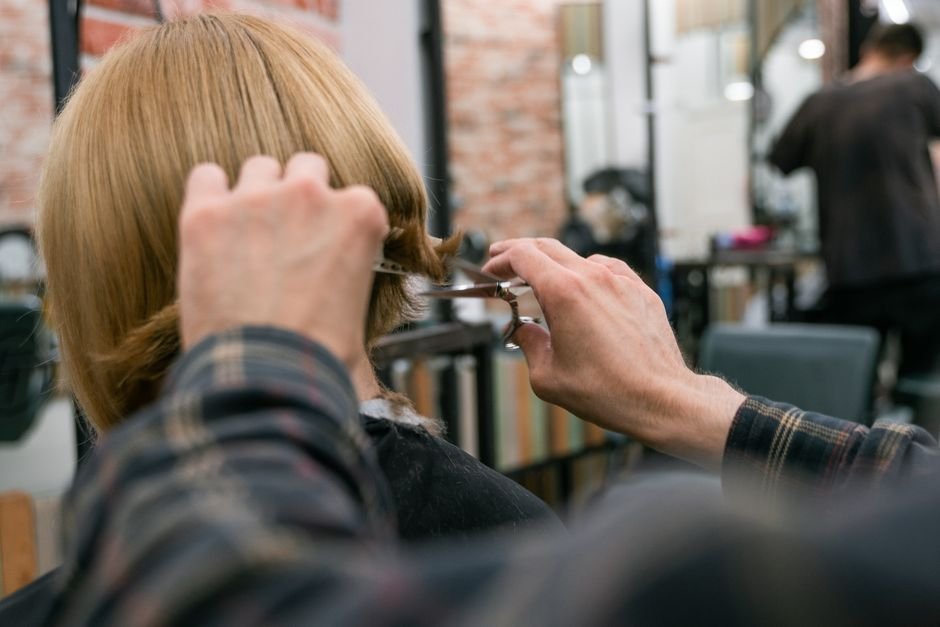Cliente sendo atendida em corte de cabelo com sorriso de satisfação