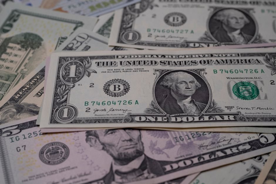 Notas de dólar e euro sobre calculadora e planilha de custos
