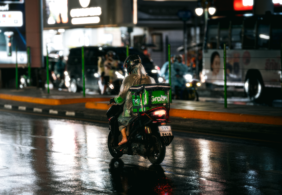 Entregador de moto na chuva com bag de delivery térmica