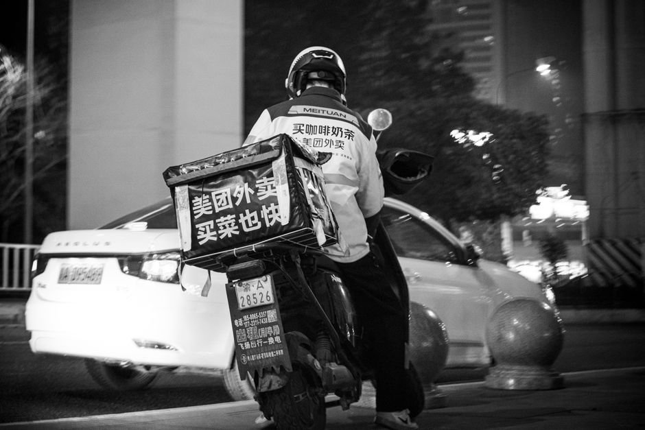 Entregador de delivery com moto e bag térmica na rua