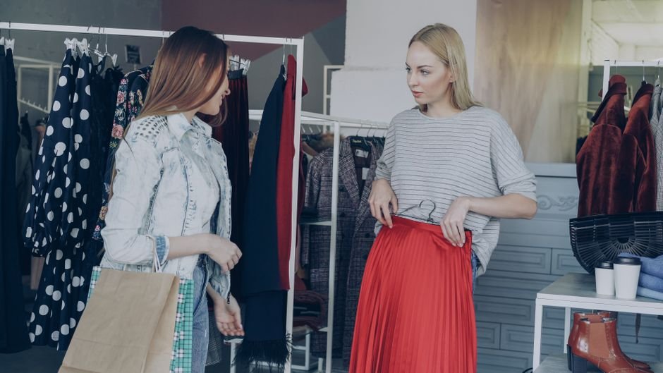 Vendedora de loja de roupas atendendo cliente com atenção