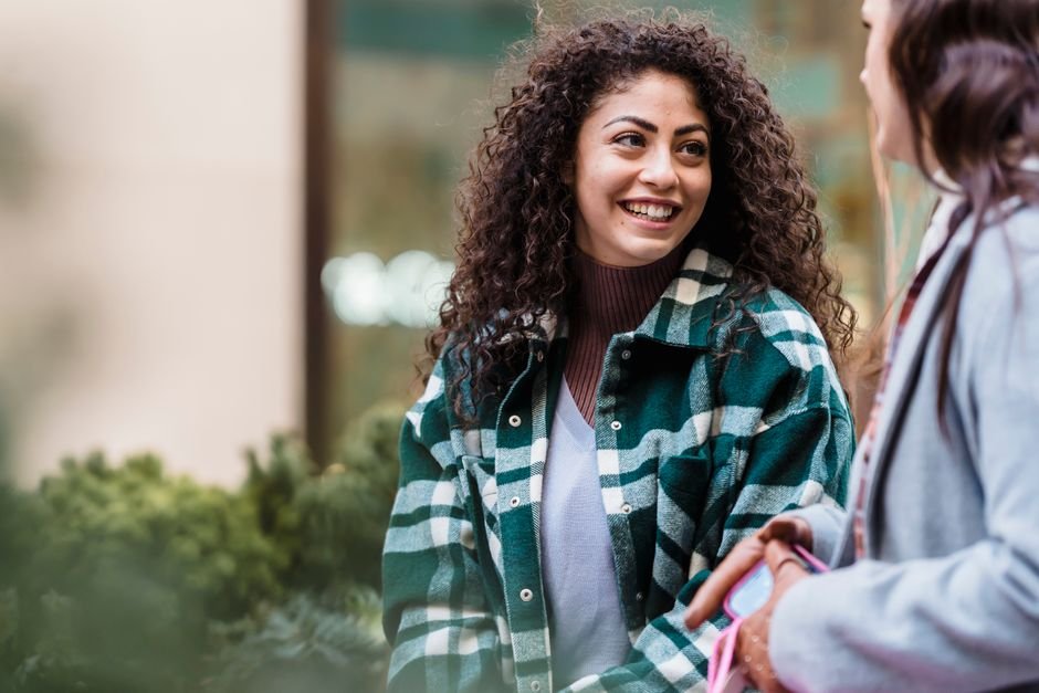 Duas amigas conversando e sorrindo sobre experiência em salão de beleza