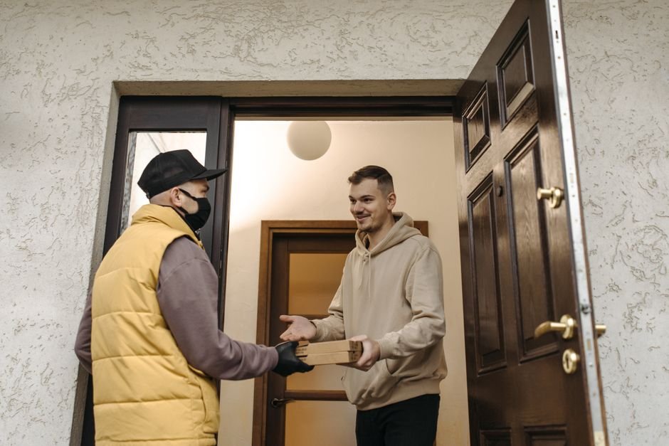 Cliente satisfeito recebendo pedido de delivery na porta de casa
